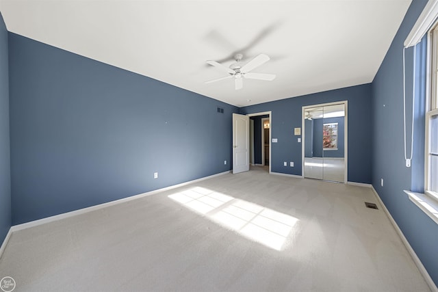 unfurnished bedroom with light carpet, visible vents, ceiling fan, and baseboards