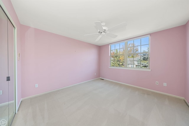 unfurnished bedroom with a closet, light carpet, baseboards, and a ceiling fan