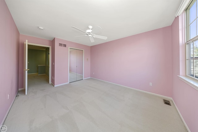 unfurnished bedroom featuring light colored carpet, baseboards, visible vents, and a closet