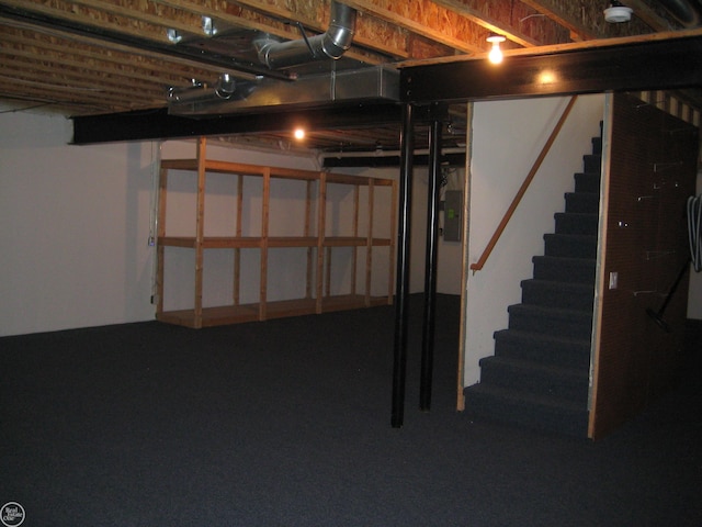 unfinished below grade area featuring electric panel and stairway