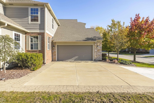 exterior space with a garage, brick siding, concrete driveway, and a shingled roof