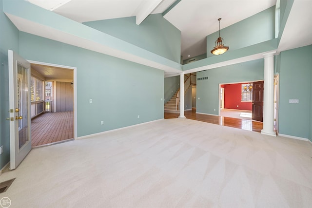 spare room with carpet flooring, stairway, high vaulted ceiling, and decorative columns