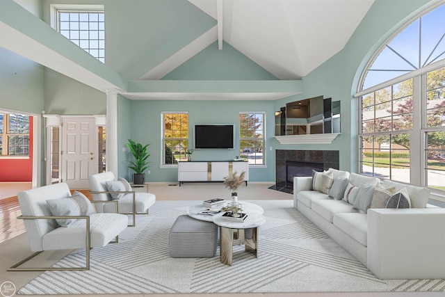 living area with baseboards, ornate columns, high vaulted ceiling, beam ceiling, and a tiled fireplace