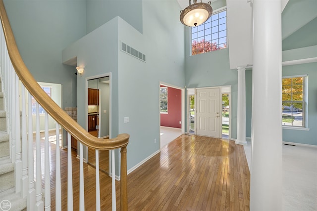 entryway featuring a wealth of natural light, visible vents, hardwood / wood-style flooring, and ornate columns