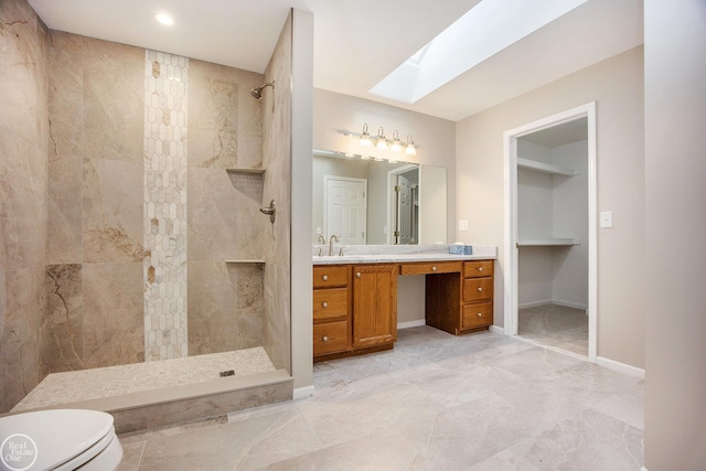 full bathroom featuring a skylight, toilet, vanity, baseboards, and walk in shower