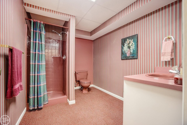 bathroom featuring a paneled ceiling, toilet, vanity, baseboards, and a stall shower