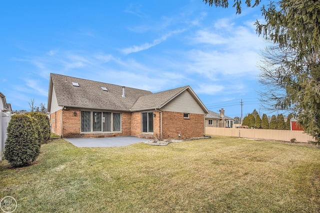 back of property featuring brick siding, a yard, a patio, a shingled roof, and fence