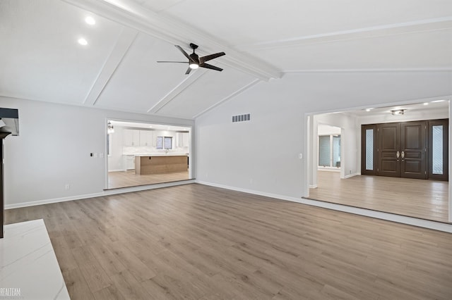 unfurnished living room with vaulted ceiling with beams, wood finished floors, visible vents, baseboards, and a ceiling fan