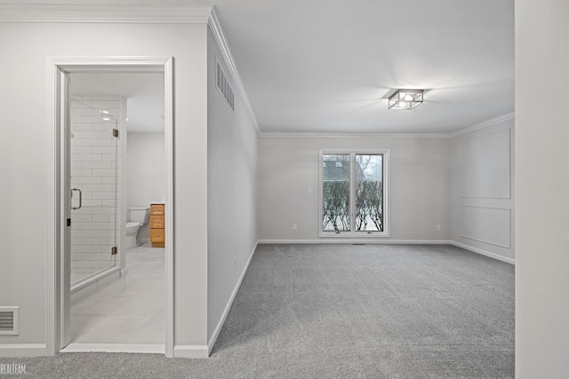 spare room featuring carpet, visible vents, baseboards, and crown molding