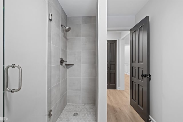 bathroom with a stall shower, wood finished floors, and baseboards