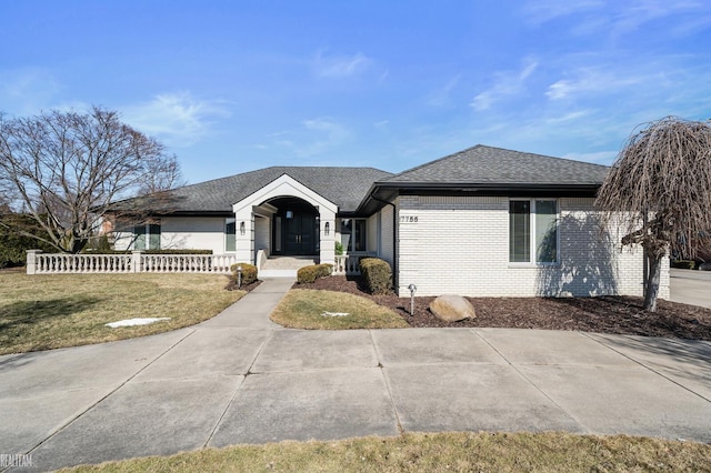 single story home with roof with shingles, a front lawn, and brick siding