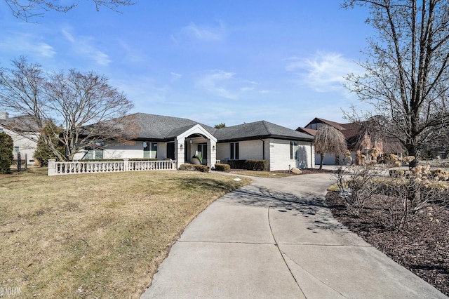 view of front of house with brick siding, a shingled roof, fence, driveway, and a front lawn