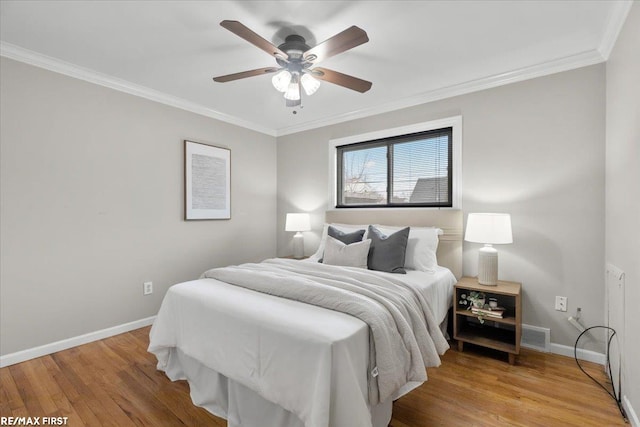 bedroom with ceiling fan, crown molding, baseboards, and wood finished floors