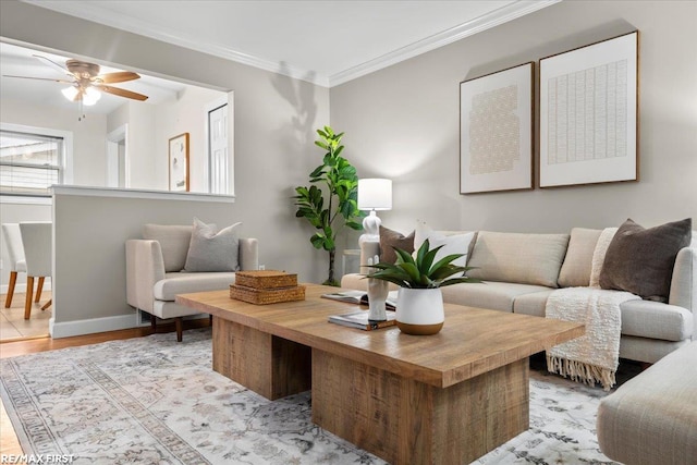 living room featuring light wood-type flooring, baseboards, ornamental molding, and ceiling fan