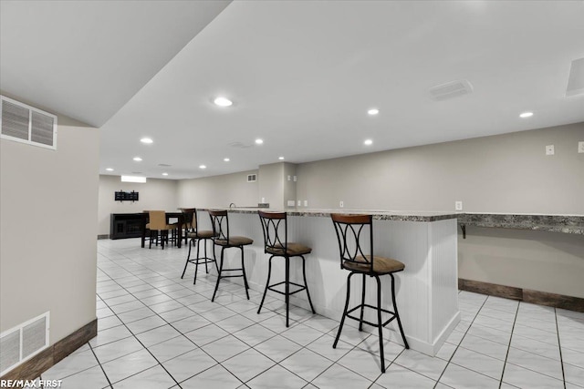 kitchen with a breakfast bar, visible vents, and recessed lighting