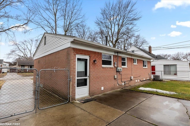 view of home's exterior with central AC, brick siding, fence, and a gate