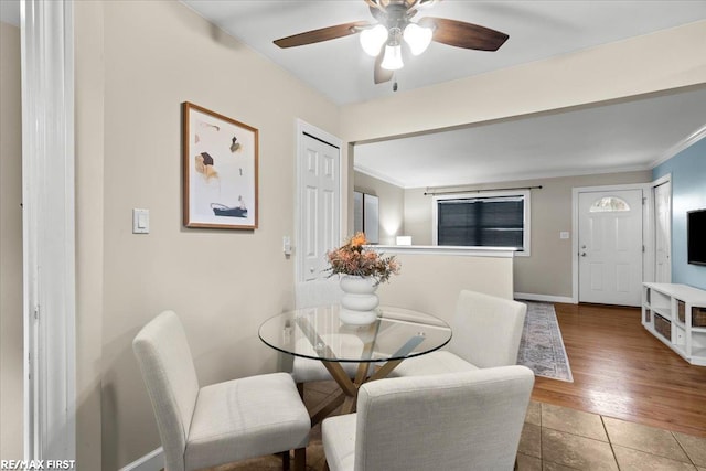 dining space with ornamental molding, tile patterned flooring, ceiling fan, and baseboards