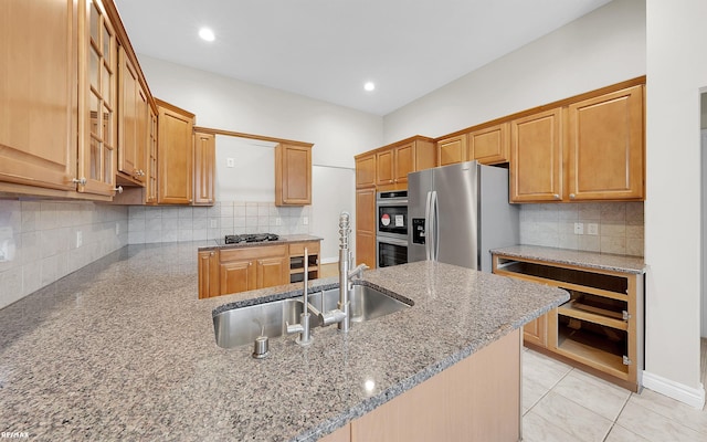 kitchen with a peninsula, a sink, appliances with stainless steel finishes, backsplash, and light stone countertops