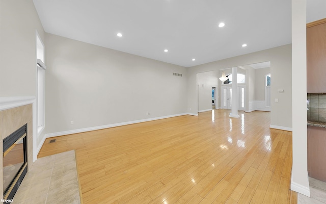 unfurnished living room featuring light wood finished floors, recessed lighting, visible vents, and a tile fireplace