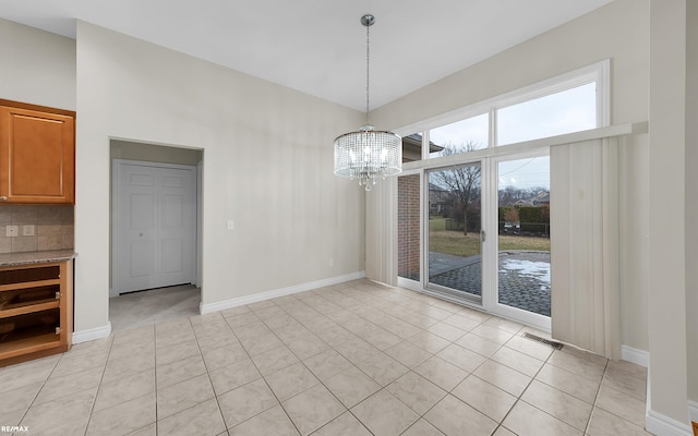 unfurnished dining area with baseboards, light tile patterned floors, visible vents, and an inviting chandelier