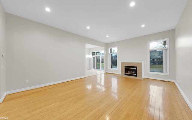 unfurnished living room with a healthy amount of sunlight, light wood-style flooring, and baseboards