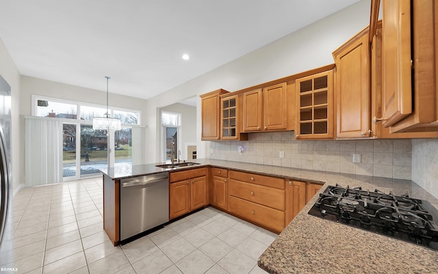 kitchen with light stone counters, black gas cooktop, backsplash, stainless steel dishwasher, and a peninsula