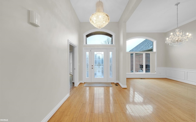 foyer with a notable chandelier, a decorative wall, and light wood finished floors