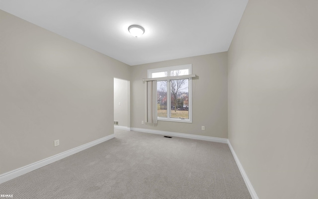 carpeted spare room featuring visible vents and baseboards