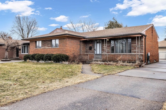 ranch-style home with covered porch, brick siding, a chimney, and a front yard