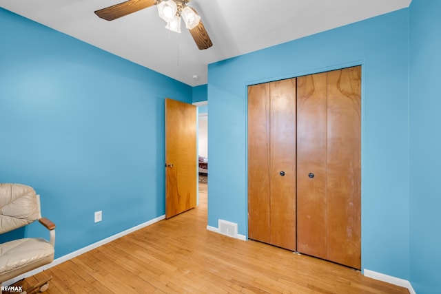 unfurnished bedroom with a closet, visible vents, ceiling fan, wood finished floors, and baseboards