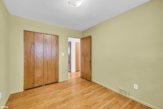 unfurnished bedroom with a closet, visible vents, light wood-style flooring, and baseboards