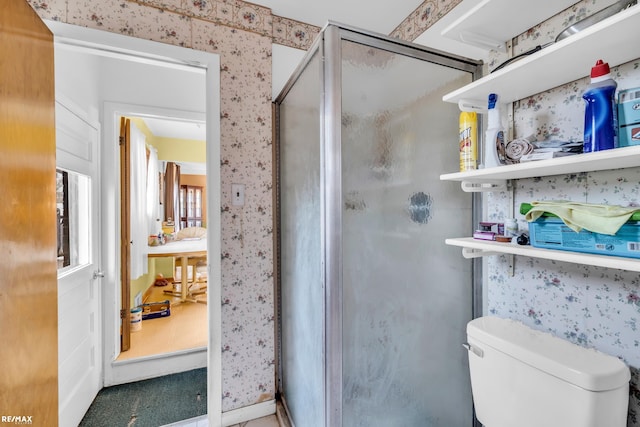 full bathroom featuring toilet, wallpapered walls, and a shower stall