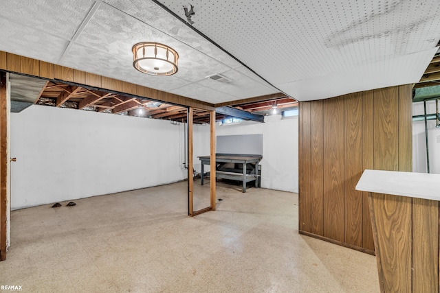 below grade area with wood walls and tile patterned floors