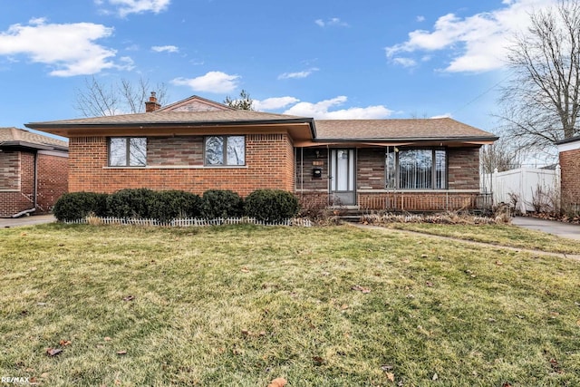 view of front of home with a front yard, brick siding, a chimney, and roof with shingles