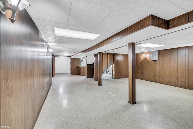 finished basement with wooden walls and tile patterned floors