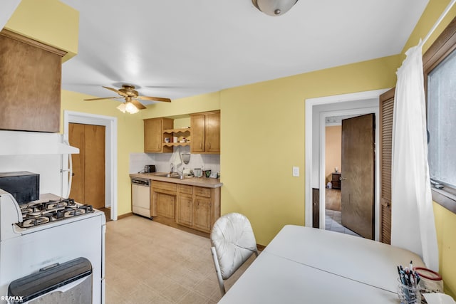 kitchen featuring light countertops, decorative backsplash, a sink, white appliances, and under cabinet range hood