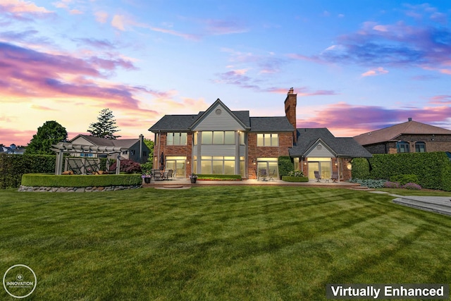 view of front of home featuring a yard, a patio area, a chimney, and brick siding