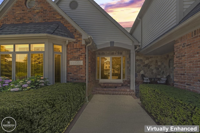 view of exterior entry with stone siding and brick siding