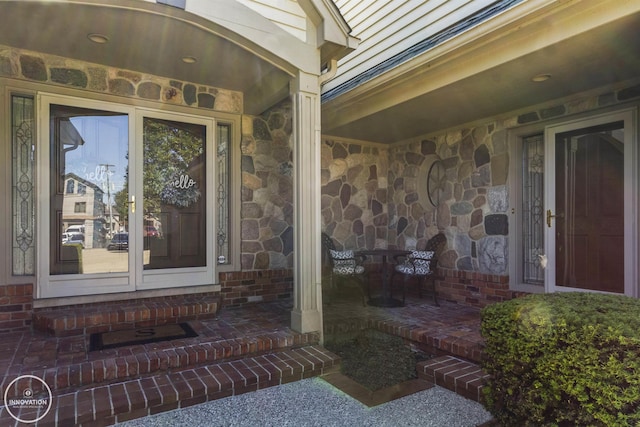 entrance to property with a porch, stone siding, and brick siding