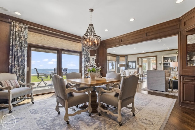 dining area with an inviting chandelier, plenty of natural light, dark wood-style flooring, and crown molding