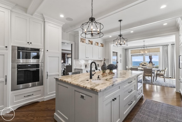 kitchen with dark wood-style flooring, stainless steel appliances, a sink, and beamed ceiling