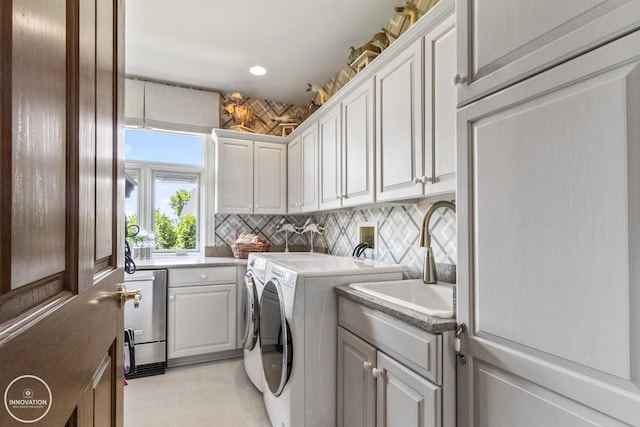 laundry room featuring a sink, light tile patterned floors, washing machine and clothes dryer, and cabinet space