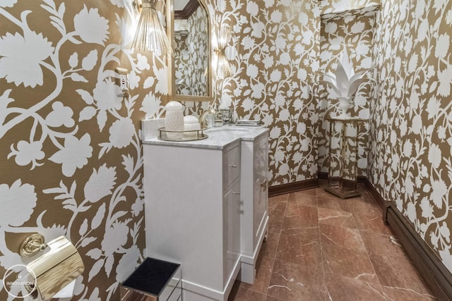 bathroom with a baseboard radiator, vanity, baseboards, and wallpapered walls