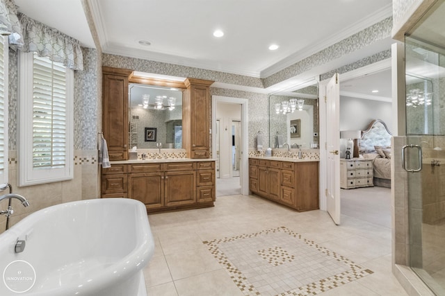 ensuite bathroom featuring a freestanding bath, ornamental molding, a sink, a shower stall, and wallpapered walls