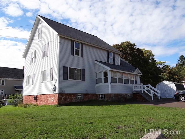 view of front facade with a storage shed, a front yard, and an outdoor structure