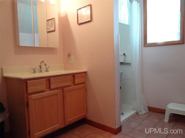 bathroom with baseboards, vanity, a shower stall, and tile patterned floors