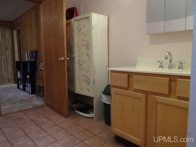 kitchen featuring light countertops, a sink, wooden walls, and light tile patterned flooring