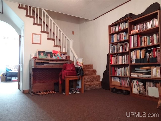 living area with arched walkways, carpet, and stairway