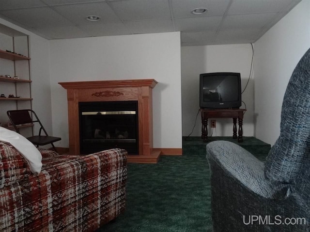 sitting room featuring carpet floors, a drop ceiling, and a glass covered fireplace