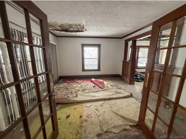 unfurnished room with crown molding, a textured ceiling, and a wealth of natural light